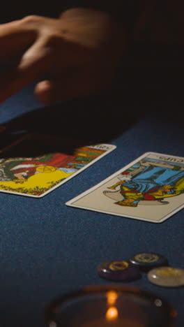 Vertical-Video-Close-Up-Of-Woman-Giving-Tarot-Card-Reading-On-Candlelit-Table-1